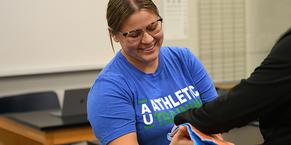 Female Athletic Training student working on a student.