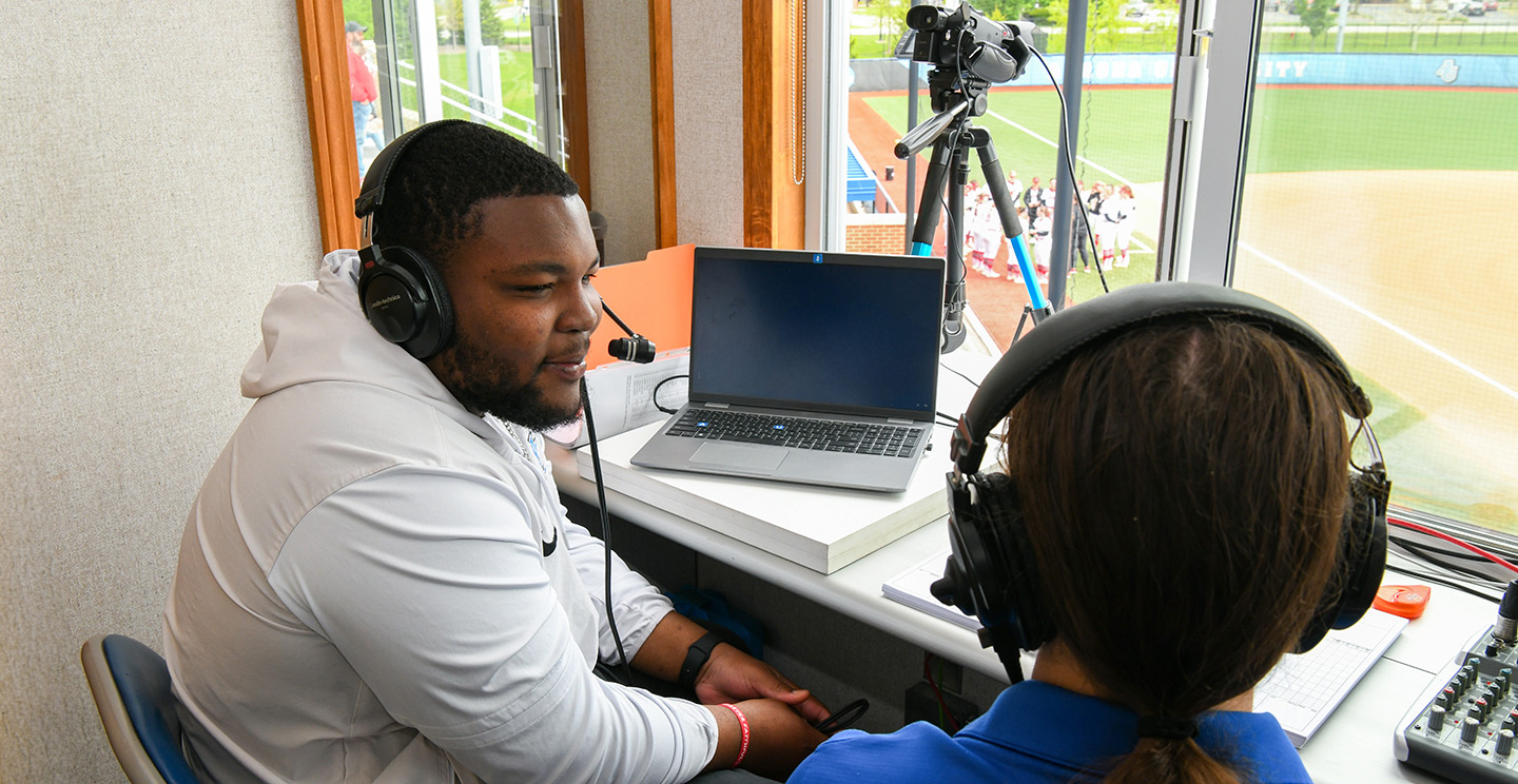 Two students in the press box at the softball stadium.