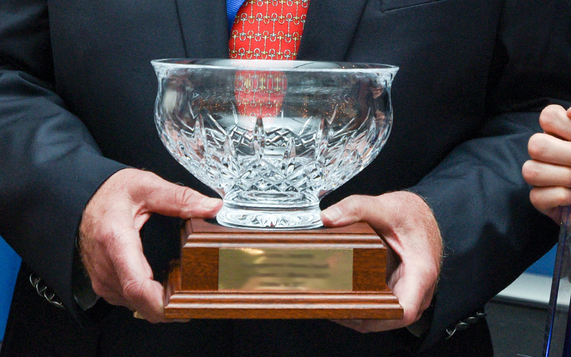 Alumni award with a glass bowl on wooden platform.