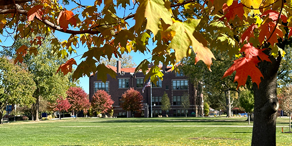 Eckhart Hall in the background with fall leaves in the foreground.