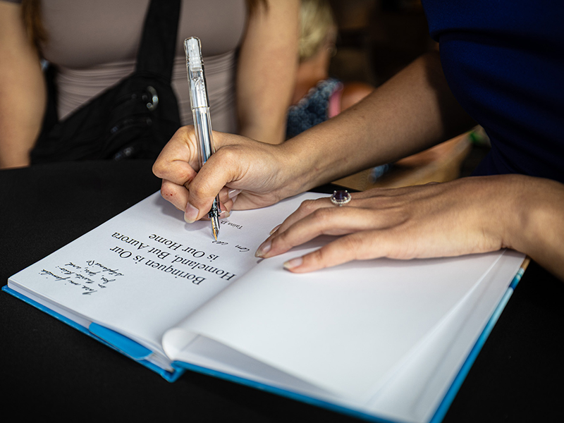 Taina Torres signs a copy of her book, “Borinquen is Our Homeland, But Aurora is Our Home”