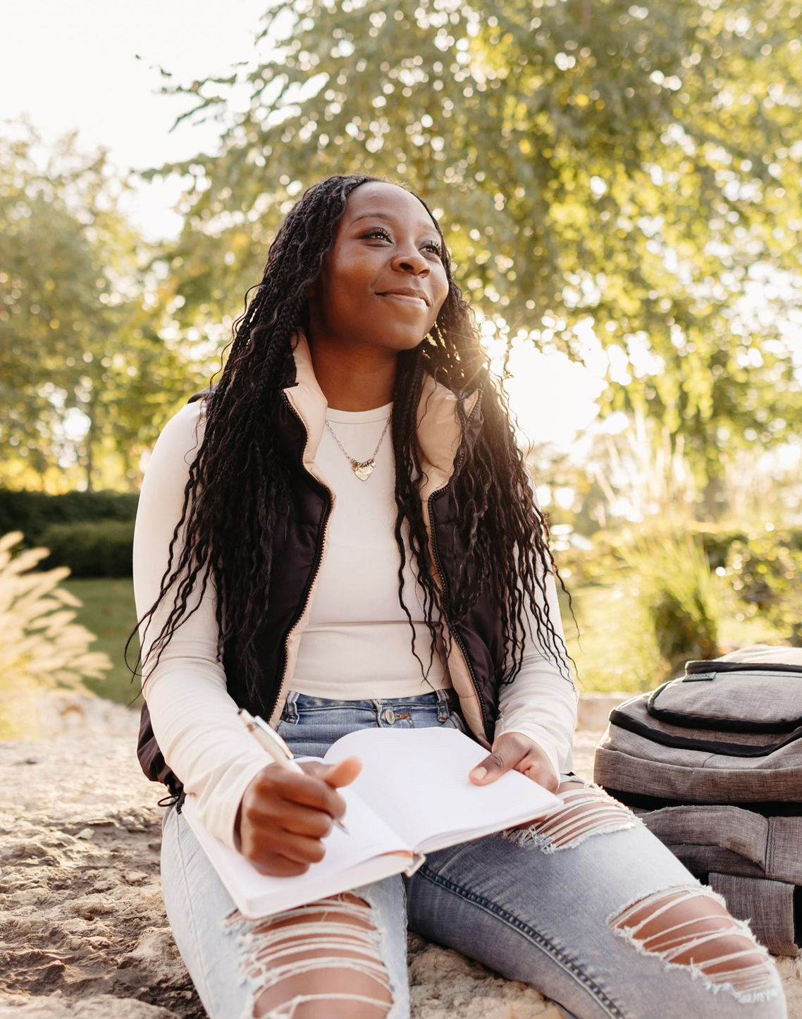 Student looking up at the sky with aspiration while working on a writing assignement.