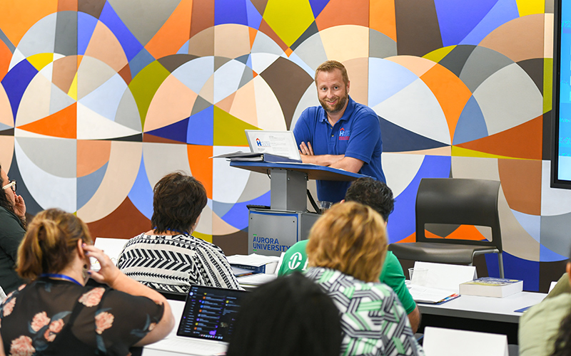 Nonprofit leadership certificate students smile as they listen to a lecture during a course meeting.