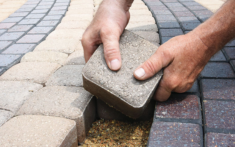 Close up image of a person laying a paver in the labyrinth.