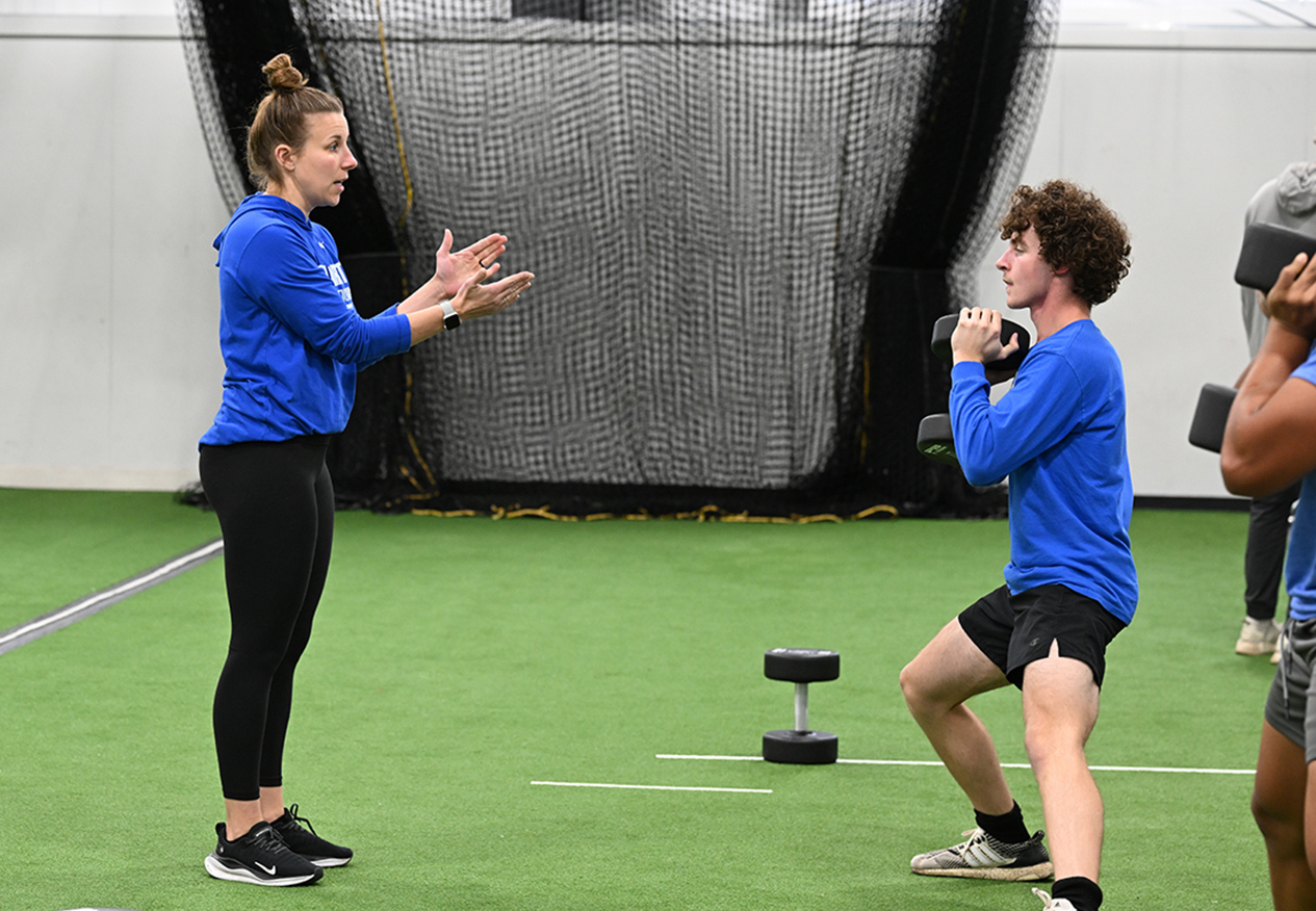 an athletic trainer works with a student in an indoor facility