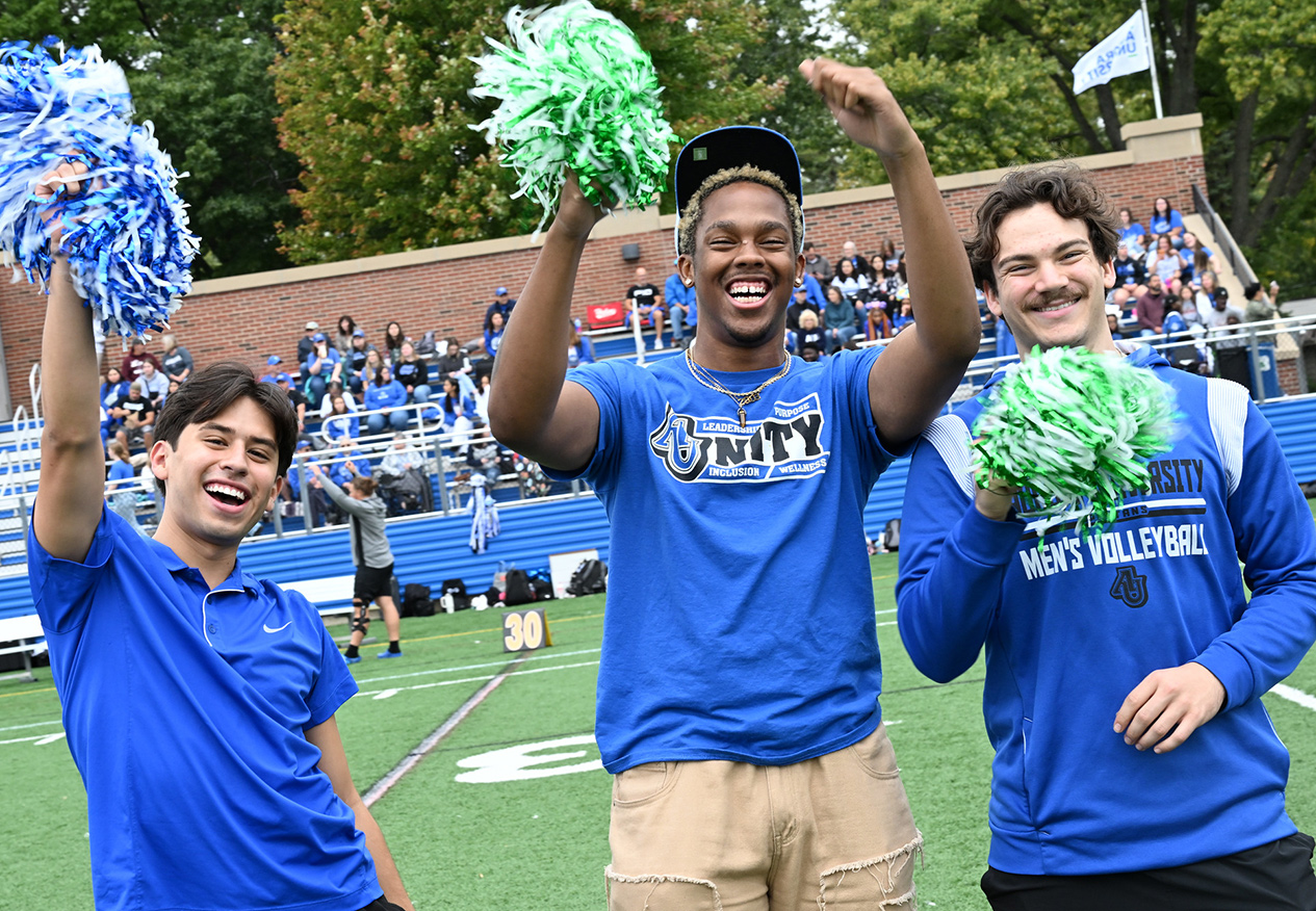students waving pom poms on Vago Field during Homecoming and Family Weekend